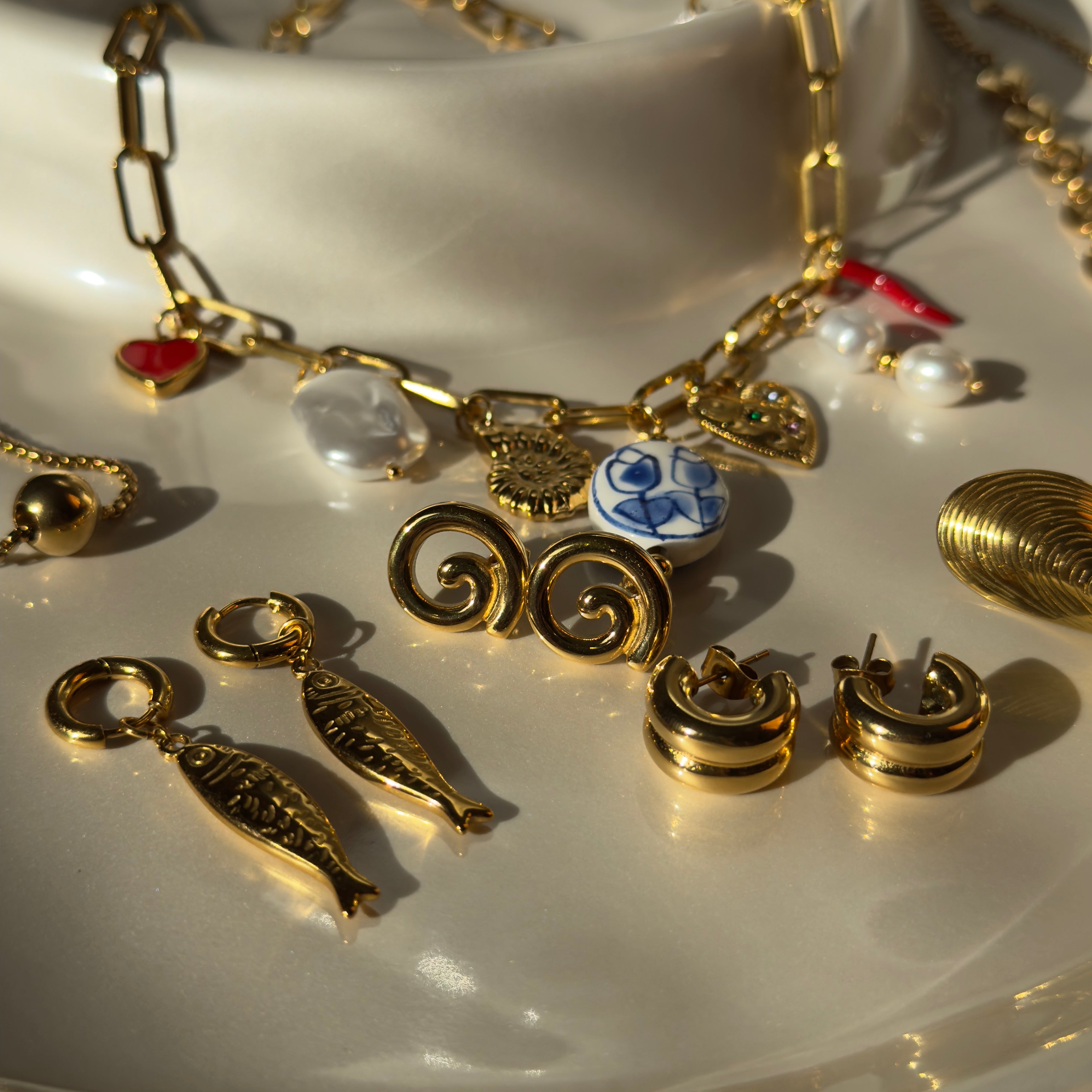 Gold jewelry with various charms on a white surface