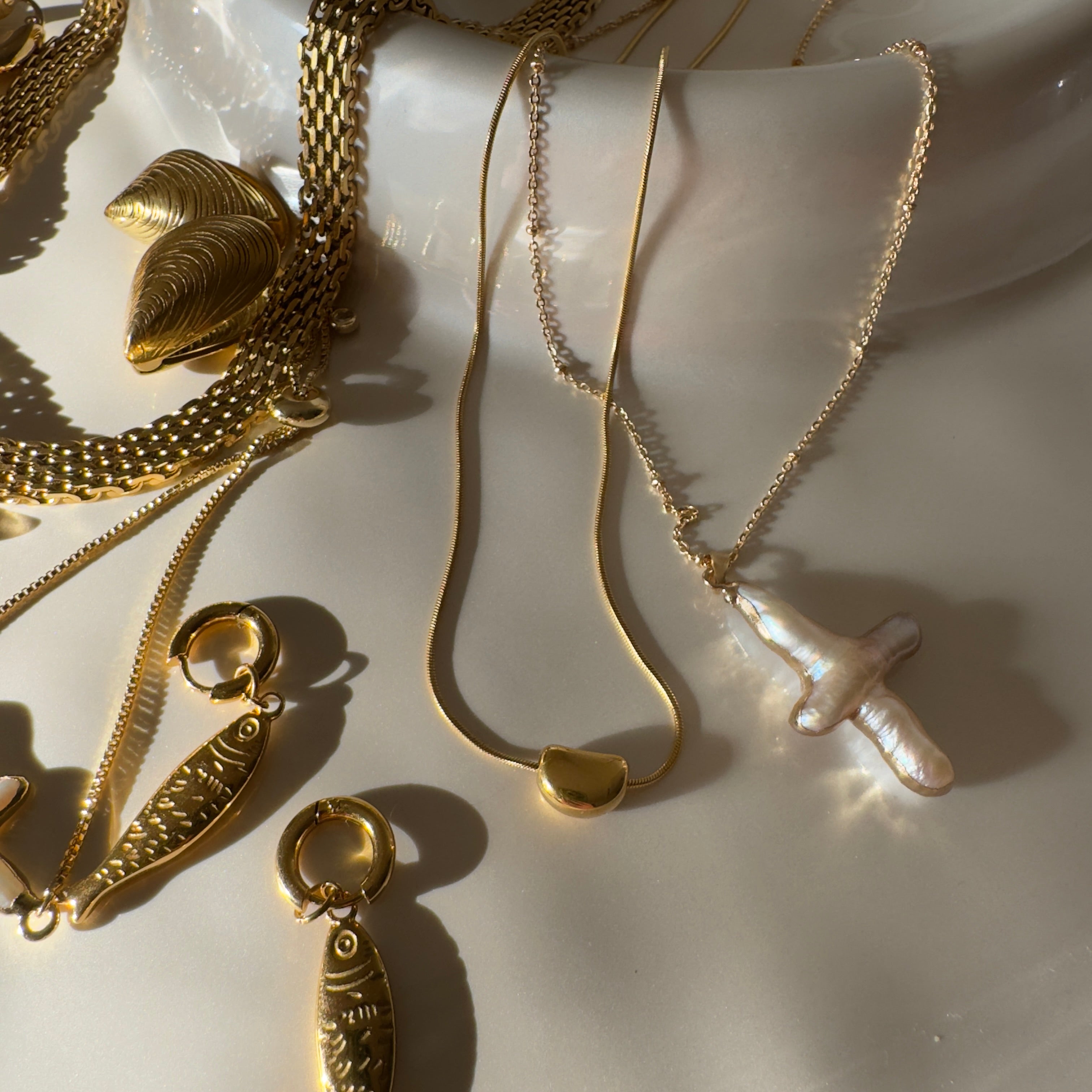 Gold jewelry including necklaces and earrings on a white surface