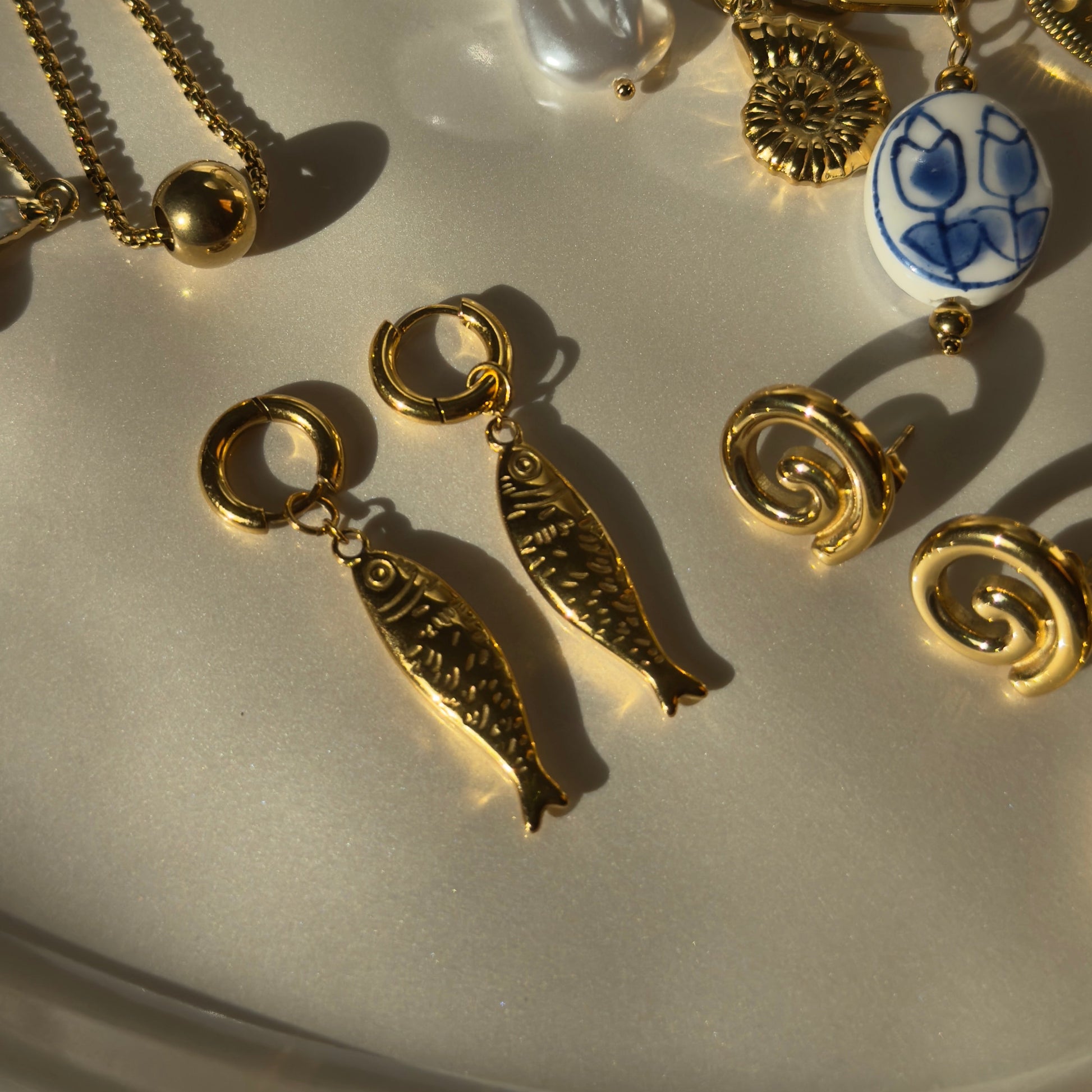 Collection of gold charm bracelets with various charms on a light background