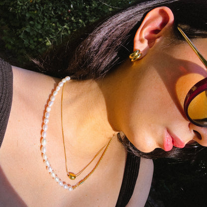 Close-up of a person wearing gold necklaces and earrings with a blurred background
