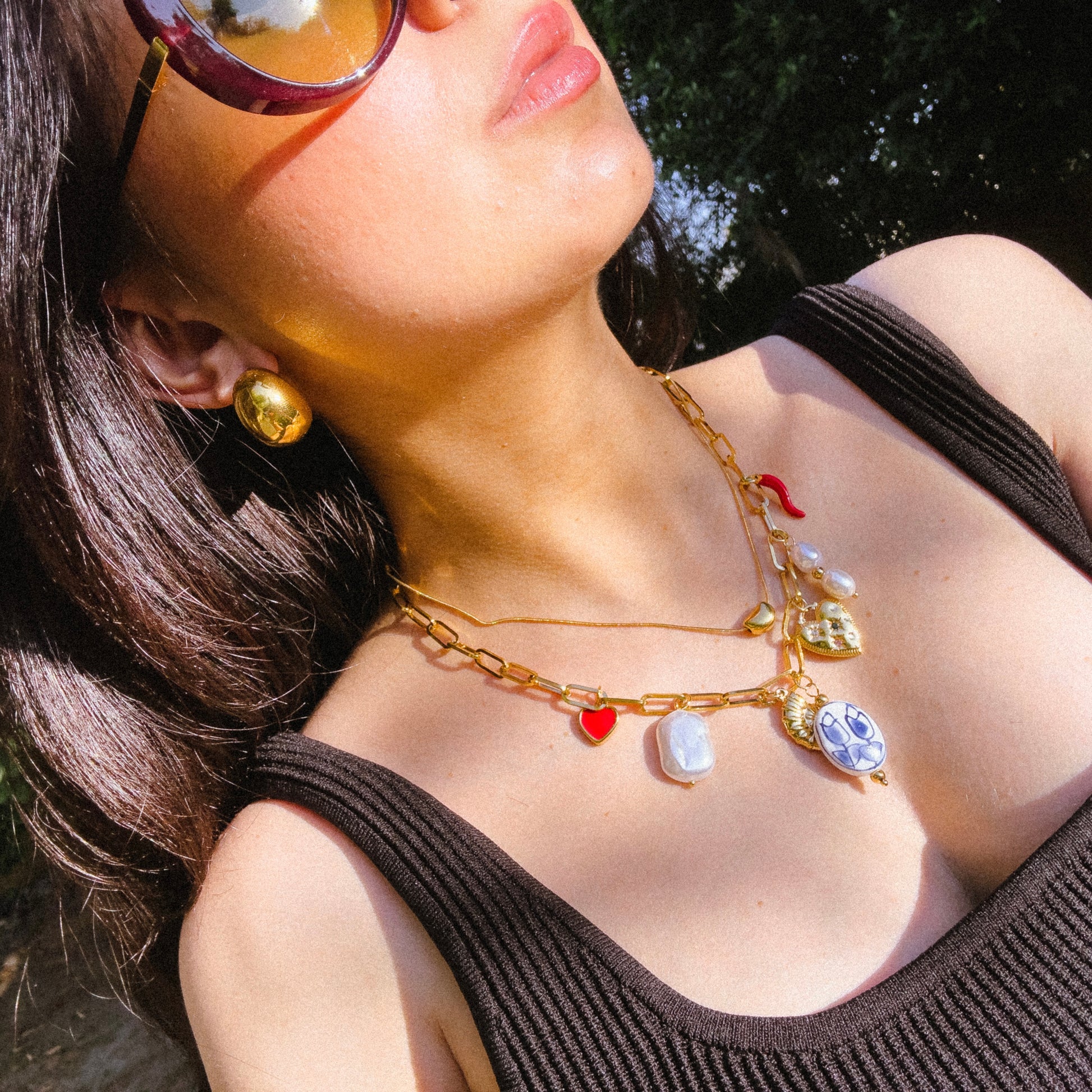 Woman wearing a gold necklace with colorful charms outdoors