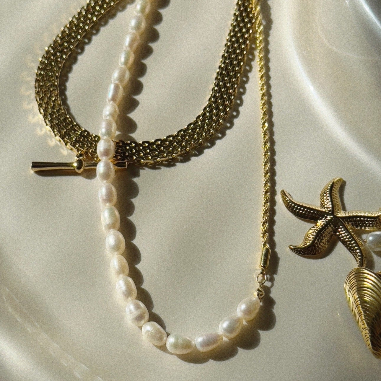 Gold and pearl necklace on a textured white surface