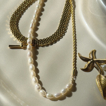 Gold and pearl necklace on a textured white surface
