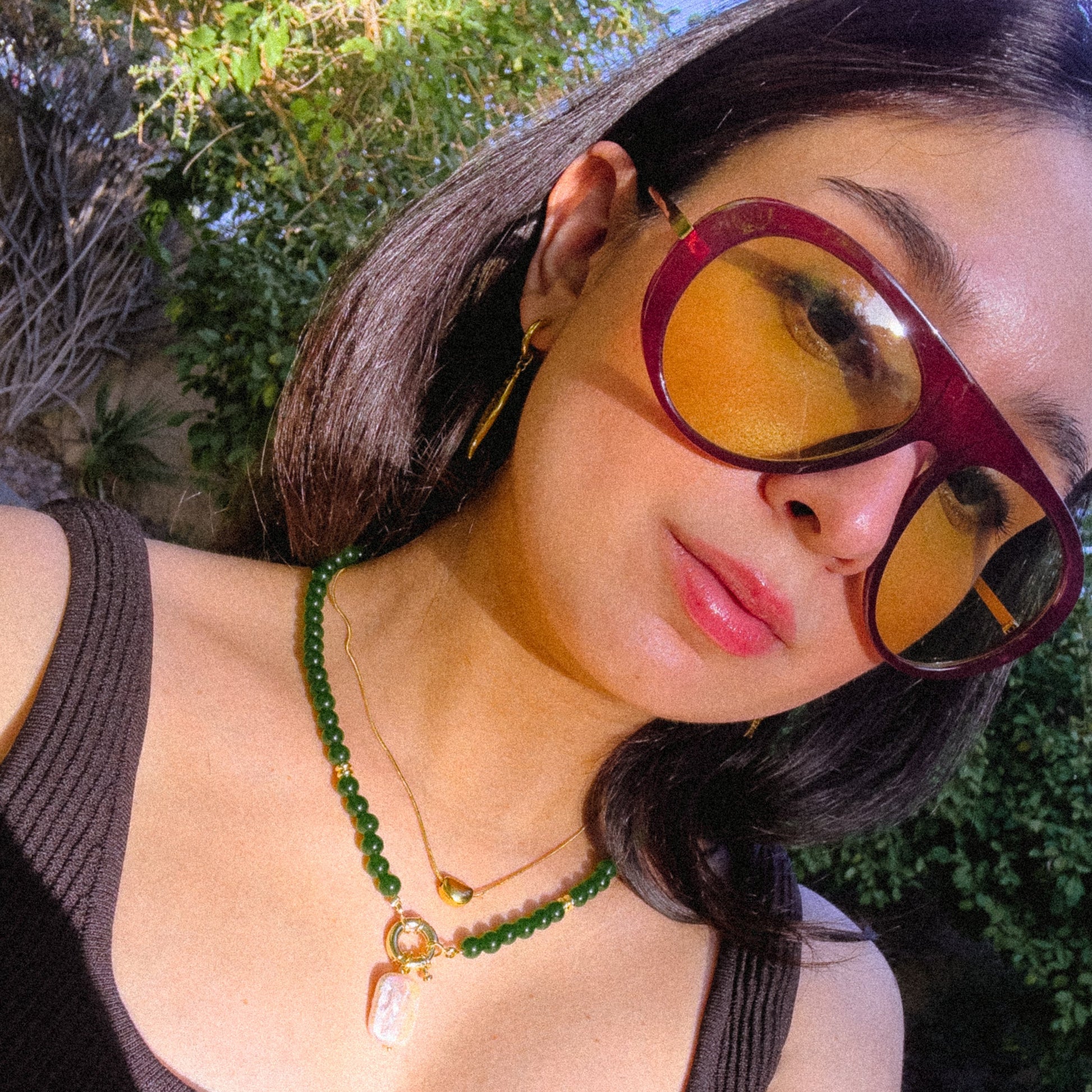 Woman wearing sunglasses with a green necklace outdoors