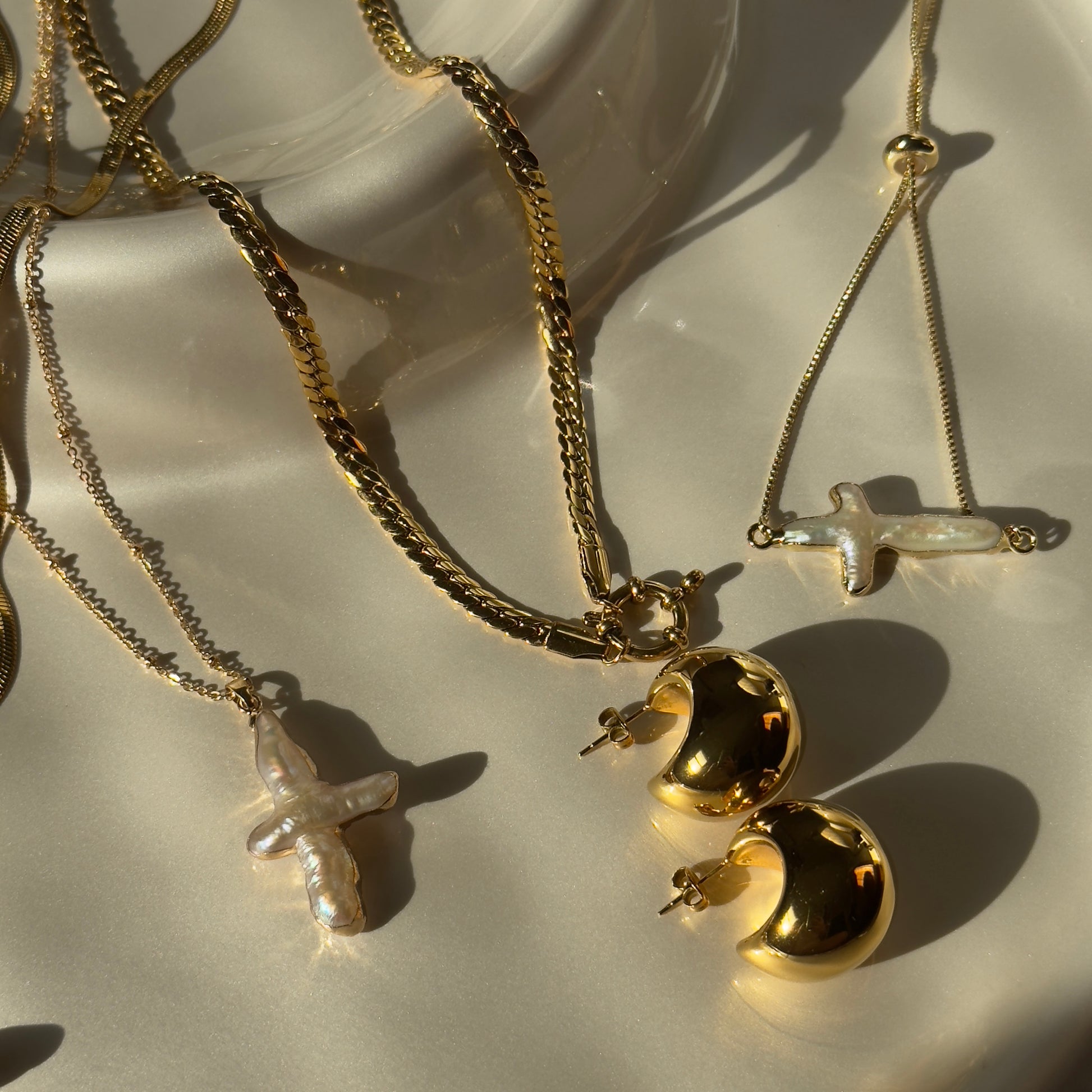 Gold necklaces with various pendants on a white surface