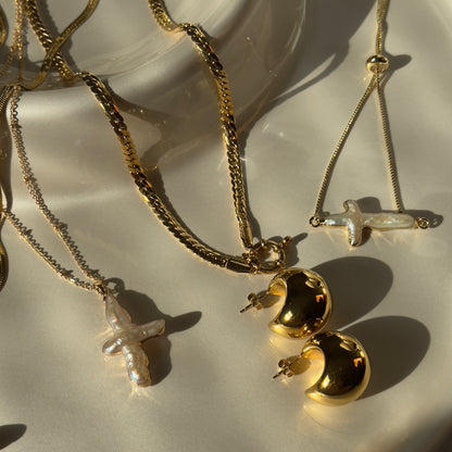 Gold necklaces with various pendants on a white surface