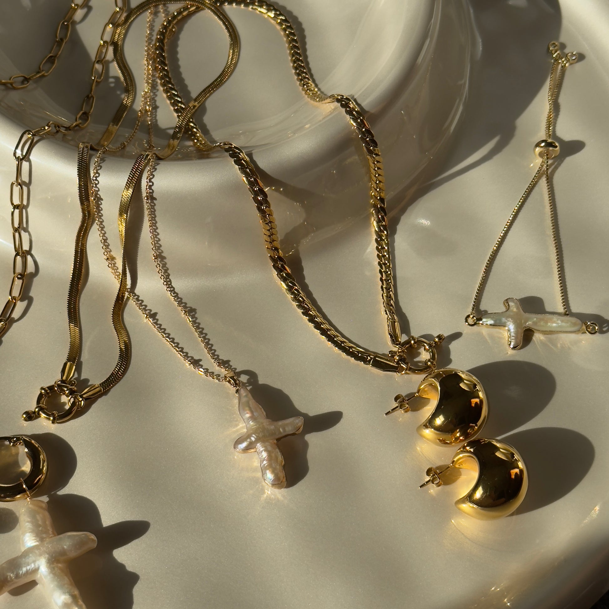 Gold jewelry including necklaces and earrings on a white surface