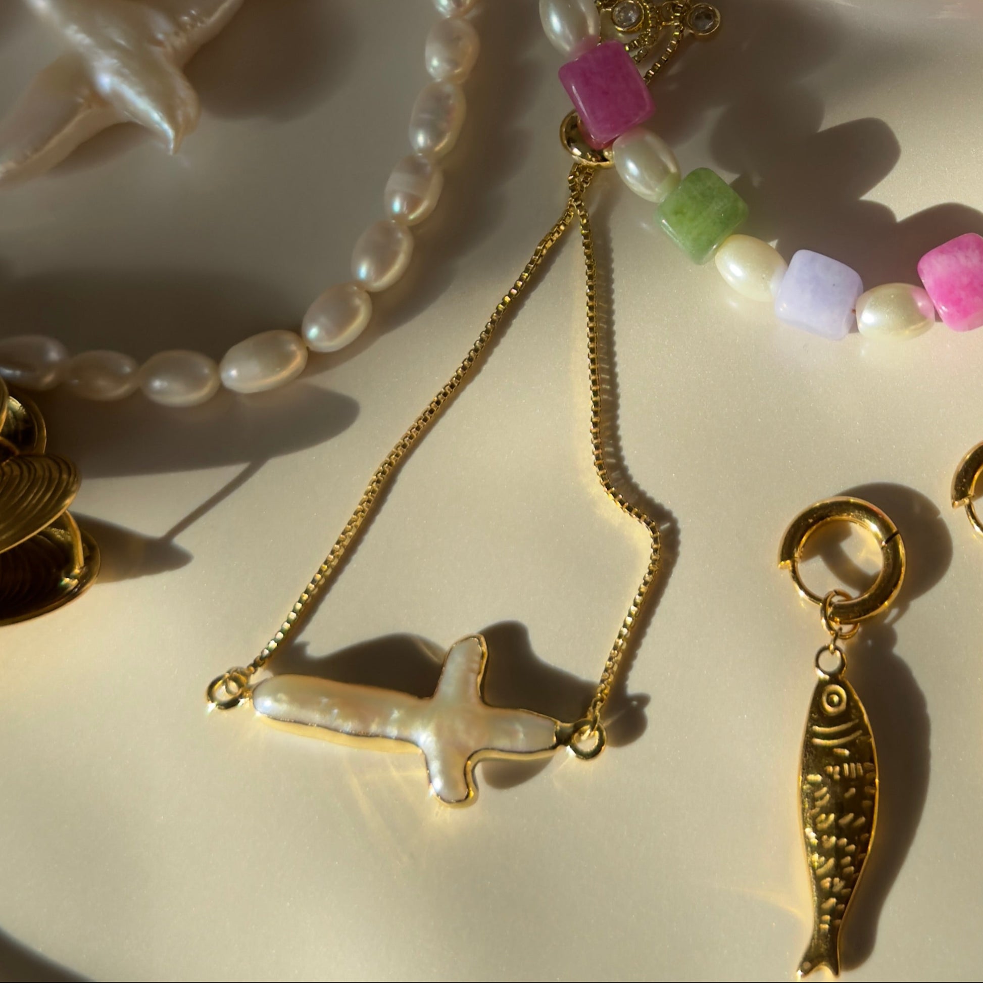Jewelry set with necklaces, earrings, and charms on a white plate